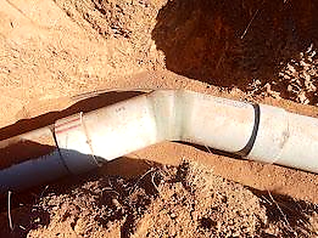 Large radius steel pipe bend bedded in a trench before backfilling