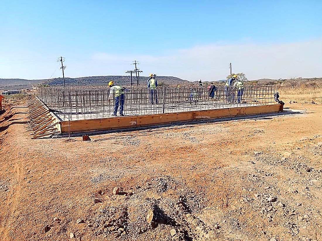 Steel fixing team working along a reinforced concrete wall base