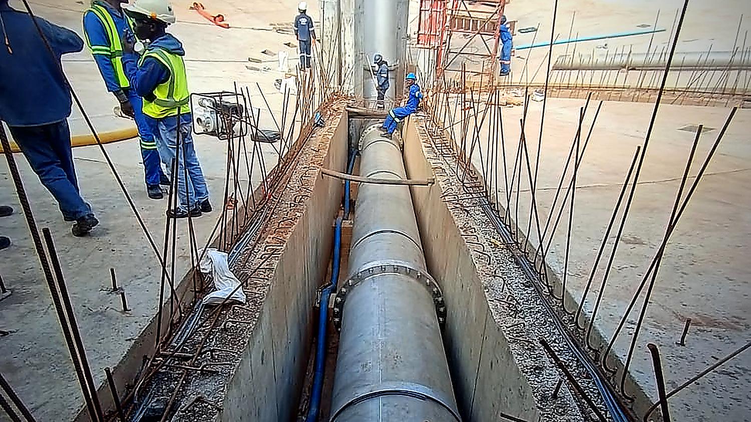Malanc Projects site team alongside a bulk water pipeline inside a new concrete reservoir