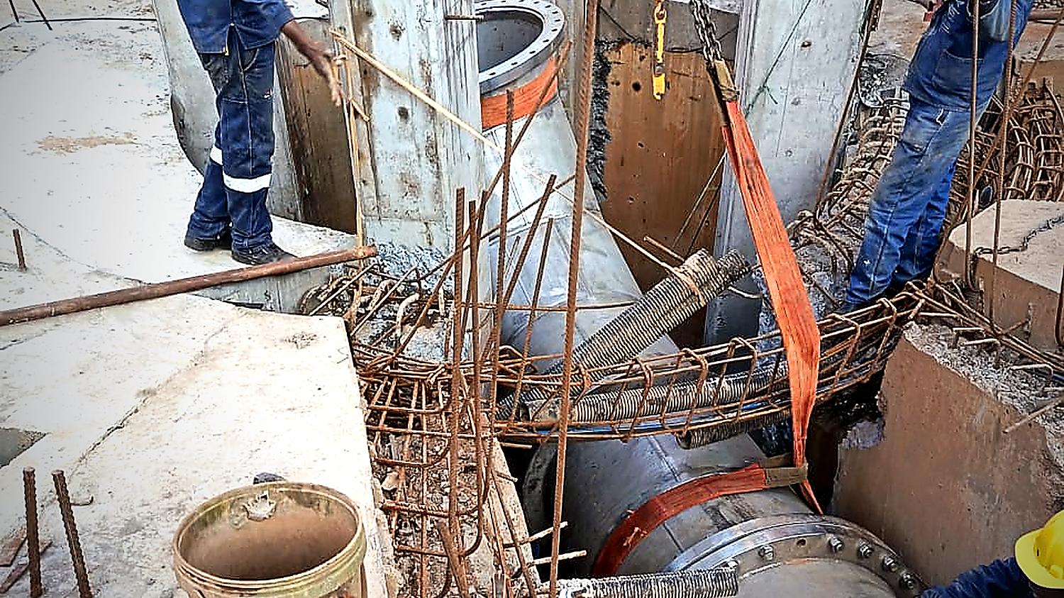 Malanc engineering crew rigging a flanged steel pipe section into a concrete chamber